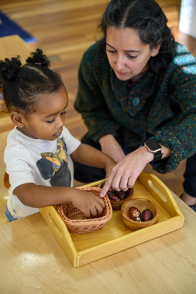Teacher with Black Child on Floor of Montessori Classroom